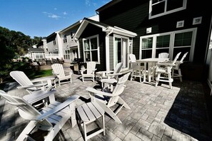 A patio area with Adirondack chairs and a table, surrounded by a house with large windows. - Bayside Resort * 1 Small Dog Allowed: Luxury 5BR B (Selbyville)