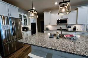 A modern kitchen with white cabinets, stainless steel appliances, granite countertops, and pendant lighting. - Bayside Resort * 1 Small Dog Allowed: Luxury 5BR B (Selbyville)