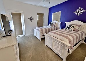 Ein Schlafzimmer mit zwei Betten, einer weißen Kommode, einem Deckenventilator und einer Kompass-Wanddekoration.