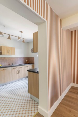 Une cuisine moderne avec des meubles en bois clair, un plan de travail noir et un sol à motifs.