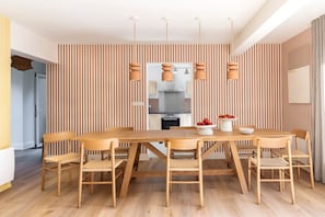 Un coin repas avec une table et des chaises en bois, un papier peint à rayures et des luminaires suspendus.