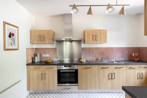 Une cuisine moderne avec des meubles en bois, une hotte en acier inoxydable et un four Bosch.