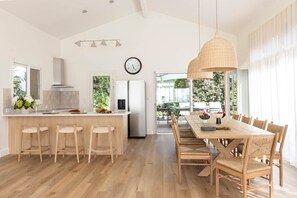 Eine moderne Küche mit einer zentralen Kochinsel, Holzstühlen und einem Esstisch mit Korbstühlen.