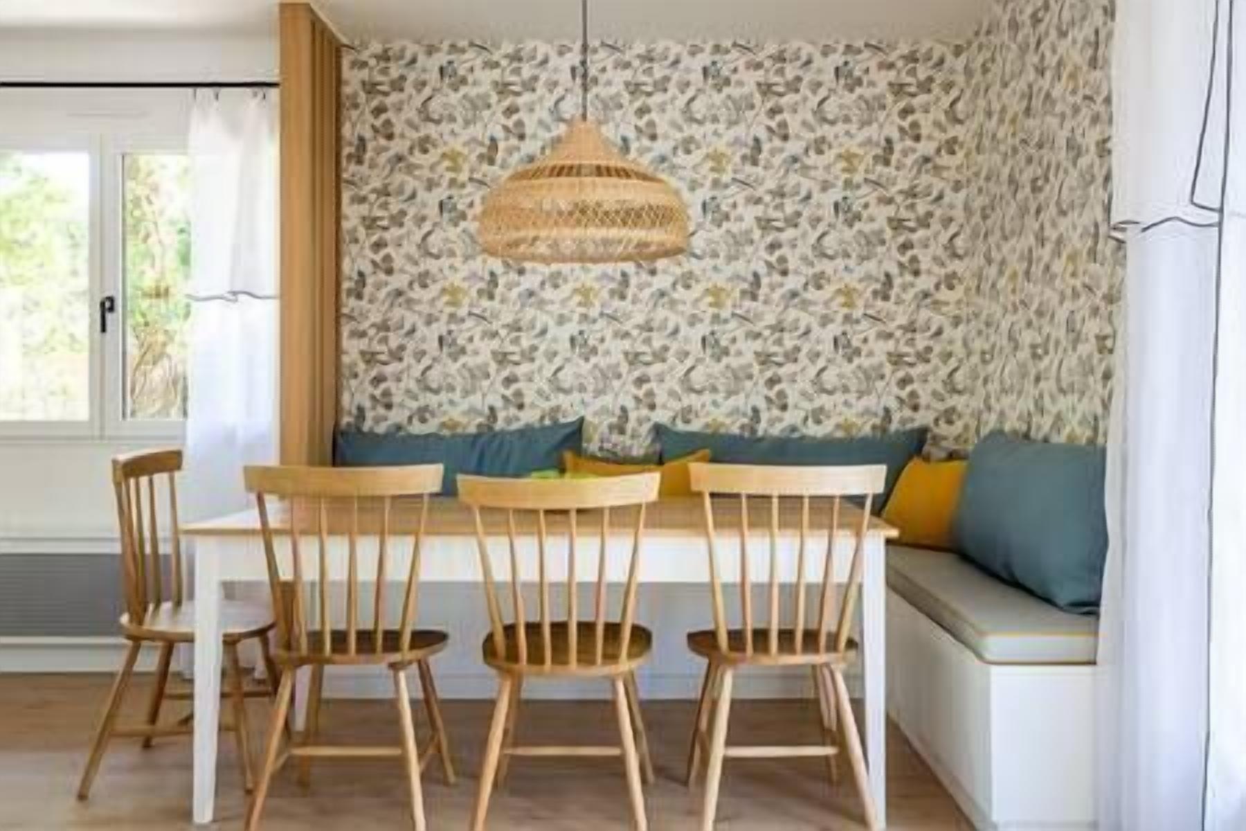 Een eethoek met een tafel, stoelen en een hangende lamp.