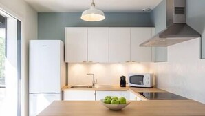 Eine moderne Küche mit weißen Schränken, einer Holzausziehtheke, einer Schüssel mit grünen Äpfeln, einer Mikrowelle und einer Kaffeemaschine.