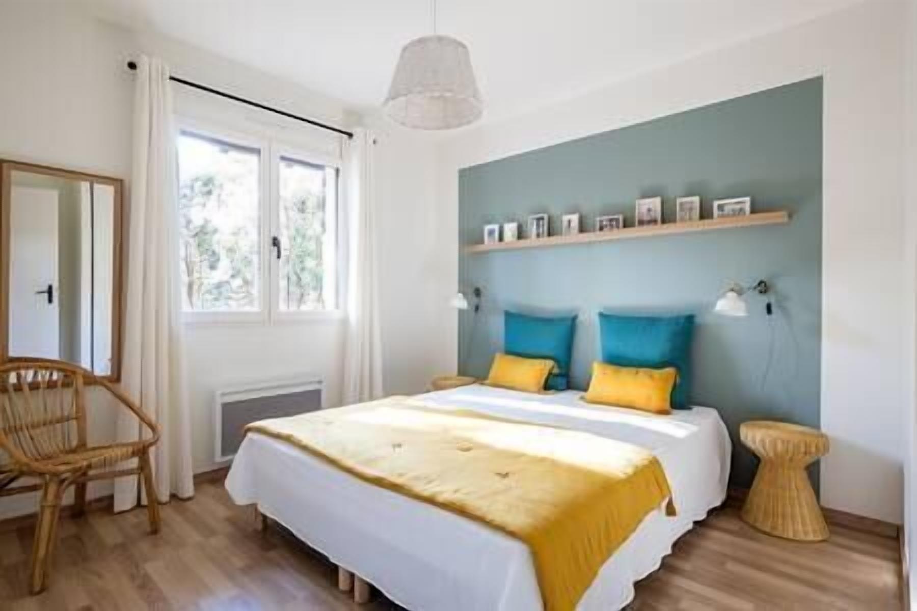 Une chambre à coucher avec un lit, une chaise, une table de chevet et une fenêtre.