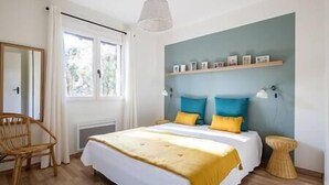 Ein Schlafzimmer mit einem Bett, einem Sessel, einem Nachttisch und einem Fenster.