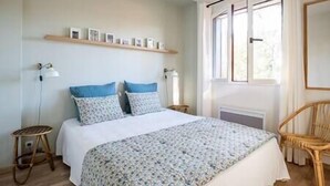 Een slaapkamer met een bed, nachtkastjes, een raam en een stoel.