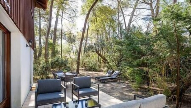 Een terras buiten met een bank, stoelen en een tafel.