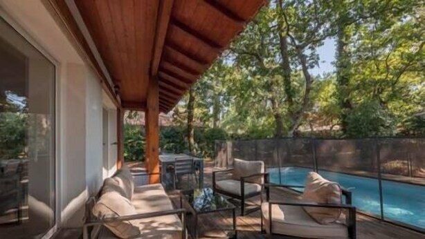A covered outdoor area with a pool, wooden deck, and seating.