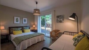 A bedroom with a bed, a chair, and a desk. There are two lamps on the nightstands.