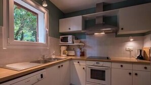 A compact kitchen with white cabinets, a microwave, a sink, and a stove.
