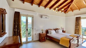 Un dormitorio con techo de madera, una cama grande, una mesita de noche, un aparador y un ventanal corredero que da a un balcón.