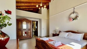 Un dormitorio con una cama de madera, un espejo grande y un jarrón de flores.