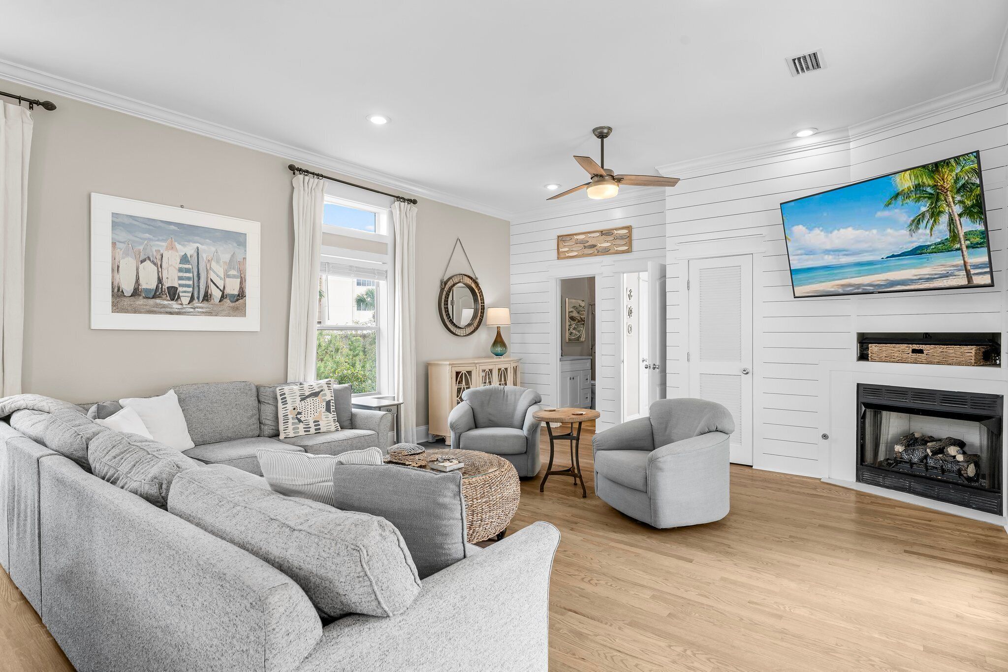 A modern living room with a gray sectional sofa, two armchairs, a small round table, and a fireplace.