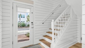 A white interior with a wooden staircase and a door leading outside. - Coastal Vue - Private Pool, Family Friendly, Gated & Private Community Beach. (Seacrest)