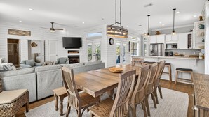A spacious living room with a large wooden dining table, grey sofa, and wooden chairs. - Coastal Vue - Private Pool, Family Friendly, Gated & Private Community Beach. (Seacrest)