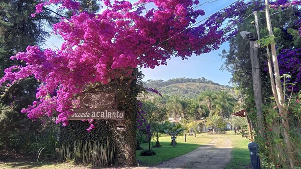 Segnaletica per 'Cousada acalanto INN' con vista su un paesaggio collinare sullo sfondo.