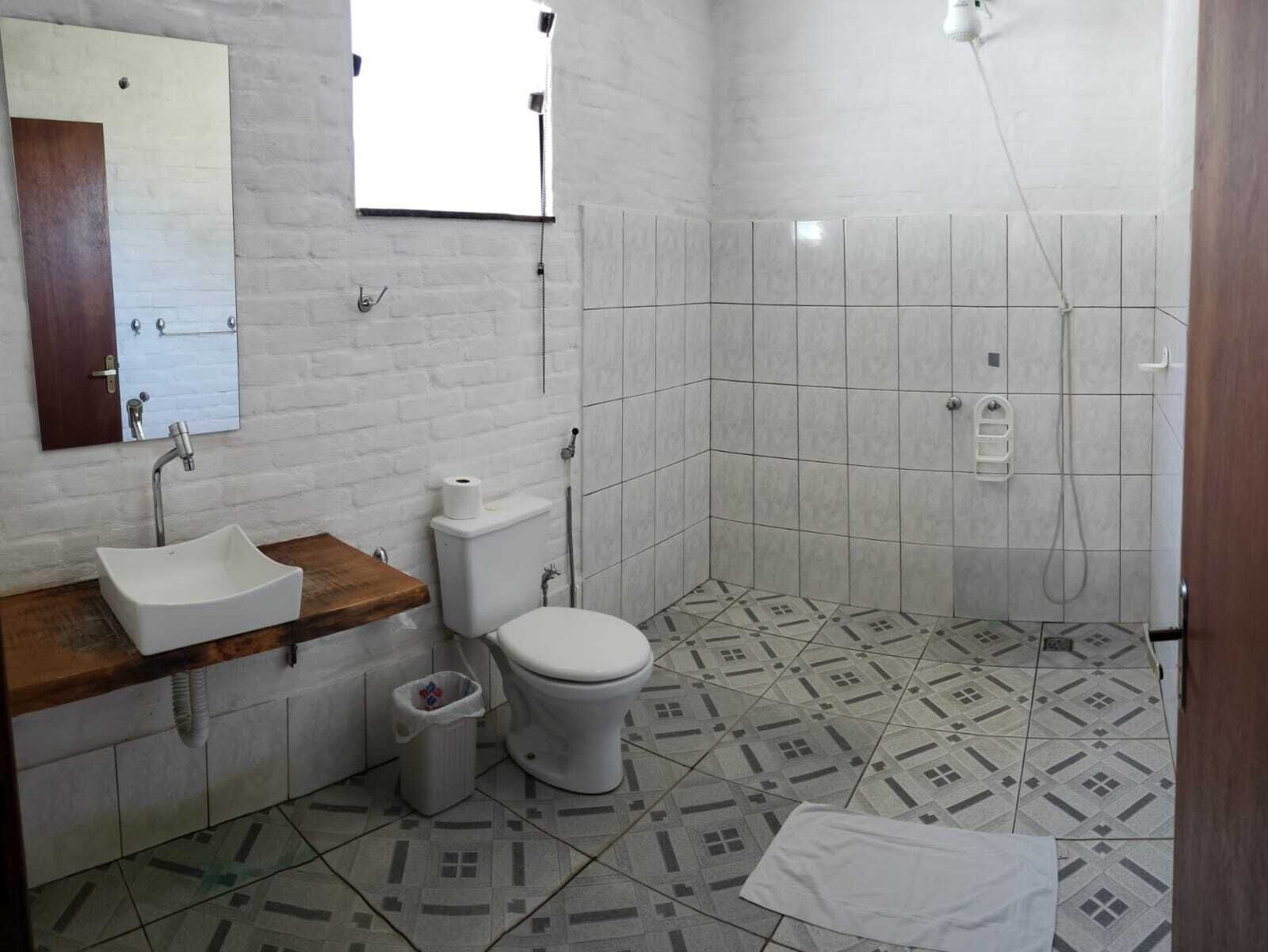 Un bagno con lavandino, WC e doccia bianchi.