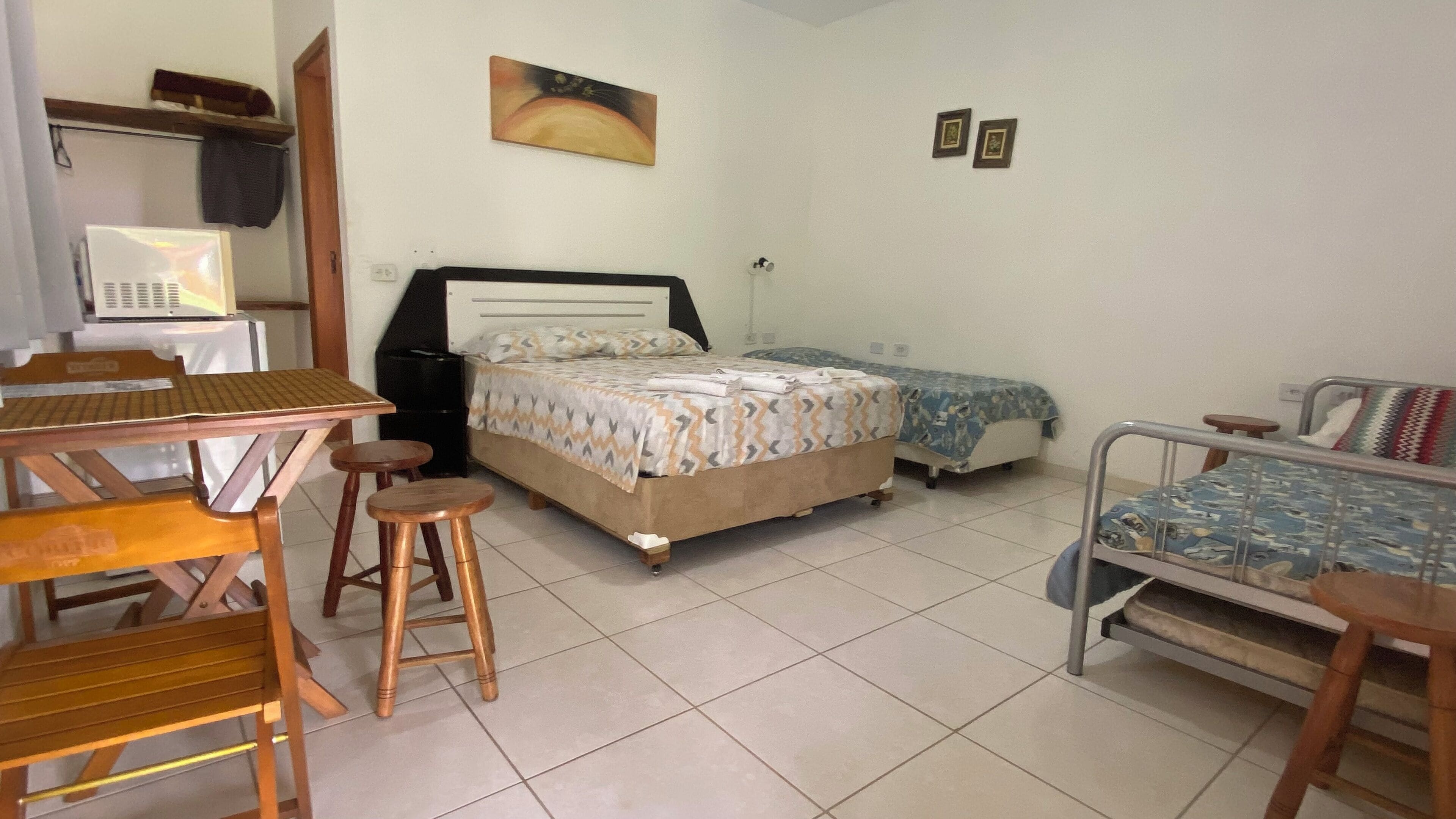 A bedroom with a bed, two bedside tables, a desk with a chair, and a small stool.