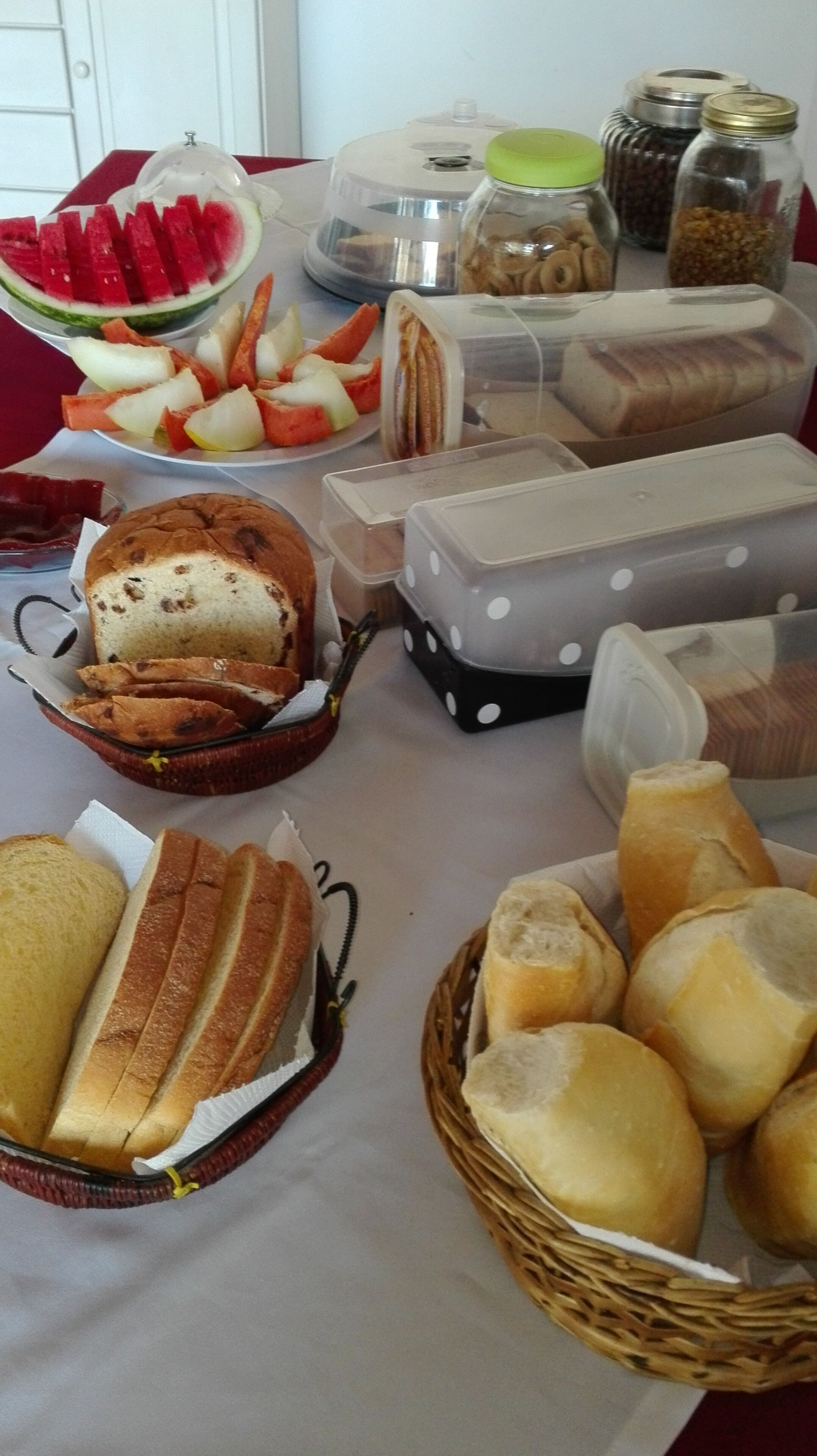 Una mesa con diversos alimentos, como pan, sándwiches y frutas.