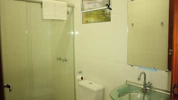 A bathroom with a glass shower enclosure, a toilet, a glass sink, and a mirror.
