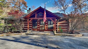 A log cabin with a flagpole, a chimney, and a porch. - Alexander's Lookout by Jackson Mountain Rentals (Gatlinburg)