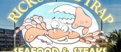 A sign for Rick's Crab Trap with a cartoon crab and the text "SEAFOOD & STEAKS".
