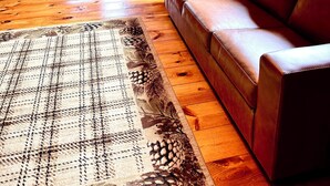Interior acogedor de una cabaña con techo de madera, un sofá, una mesa de comedor y una zona de cocina.