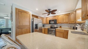 A modern kitchen with wooden cabinets, stainless steel appliances, and a large island.