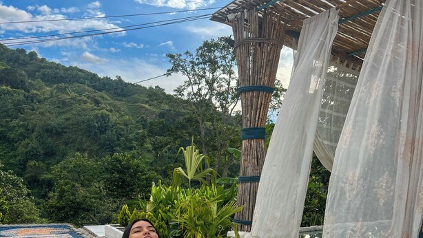 A woman relaxing in a bathtub with a view of a lush garden and a wooden pergola. - Bio Habitat Entre Montañas (Gigante)