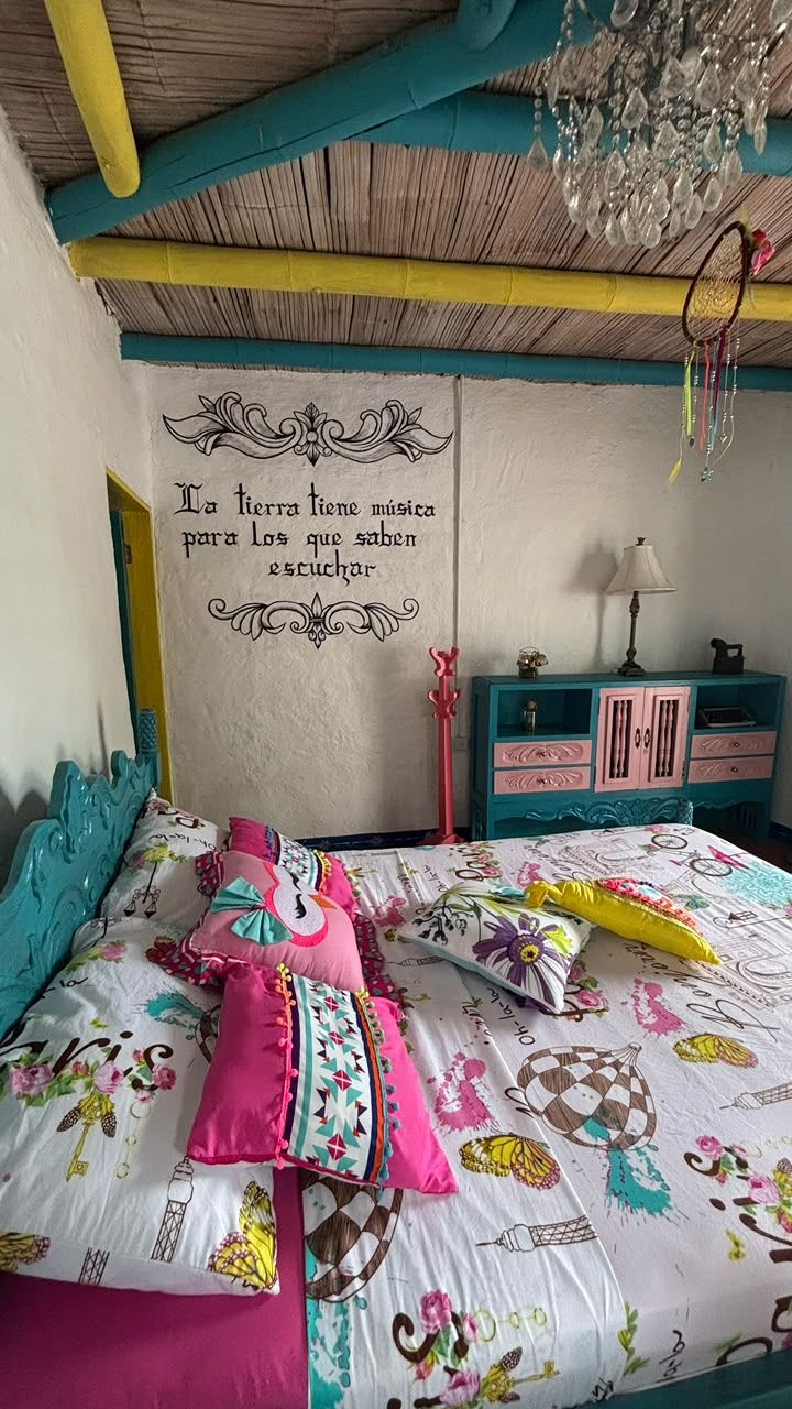 Een slaapkamer met een bed, nachtkastje, dressoir en een muur met een decoratief citaat.