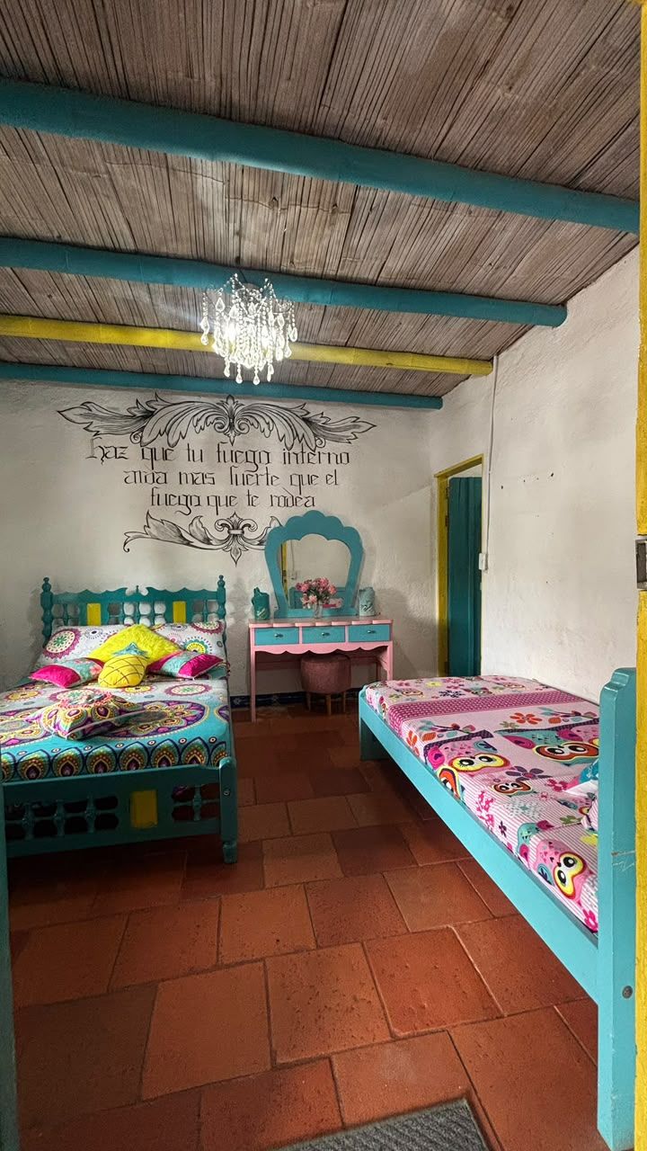 A room with two beds, a wooden ceiling, and a wall with decorative text.