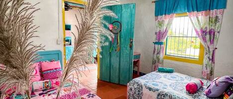 Una habitación con dos camas, techo de madera y una ventana con cortinas.