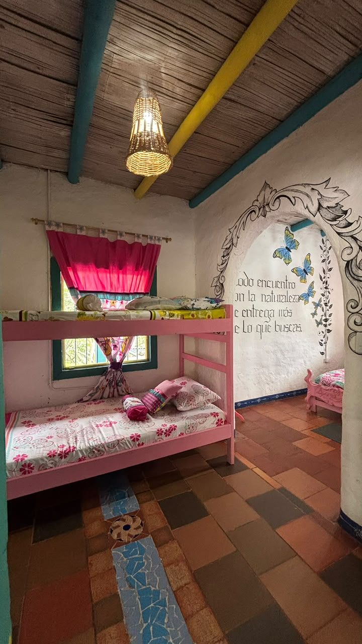 A child's bedroom with bunk beds, a window with curtains, a decorative wall with butterflies, and a patterned floor.