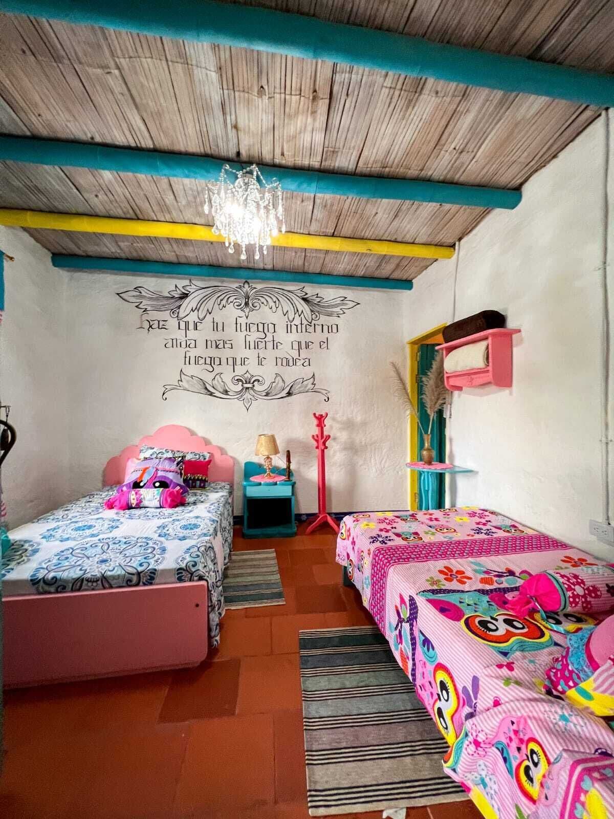 Un dormitorio acogedor con dos camas, techo de madera y una pared decorativa con texto.