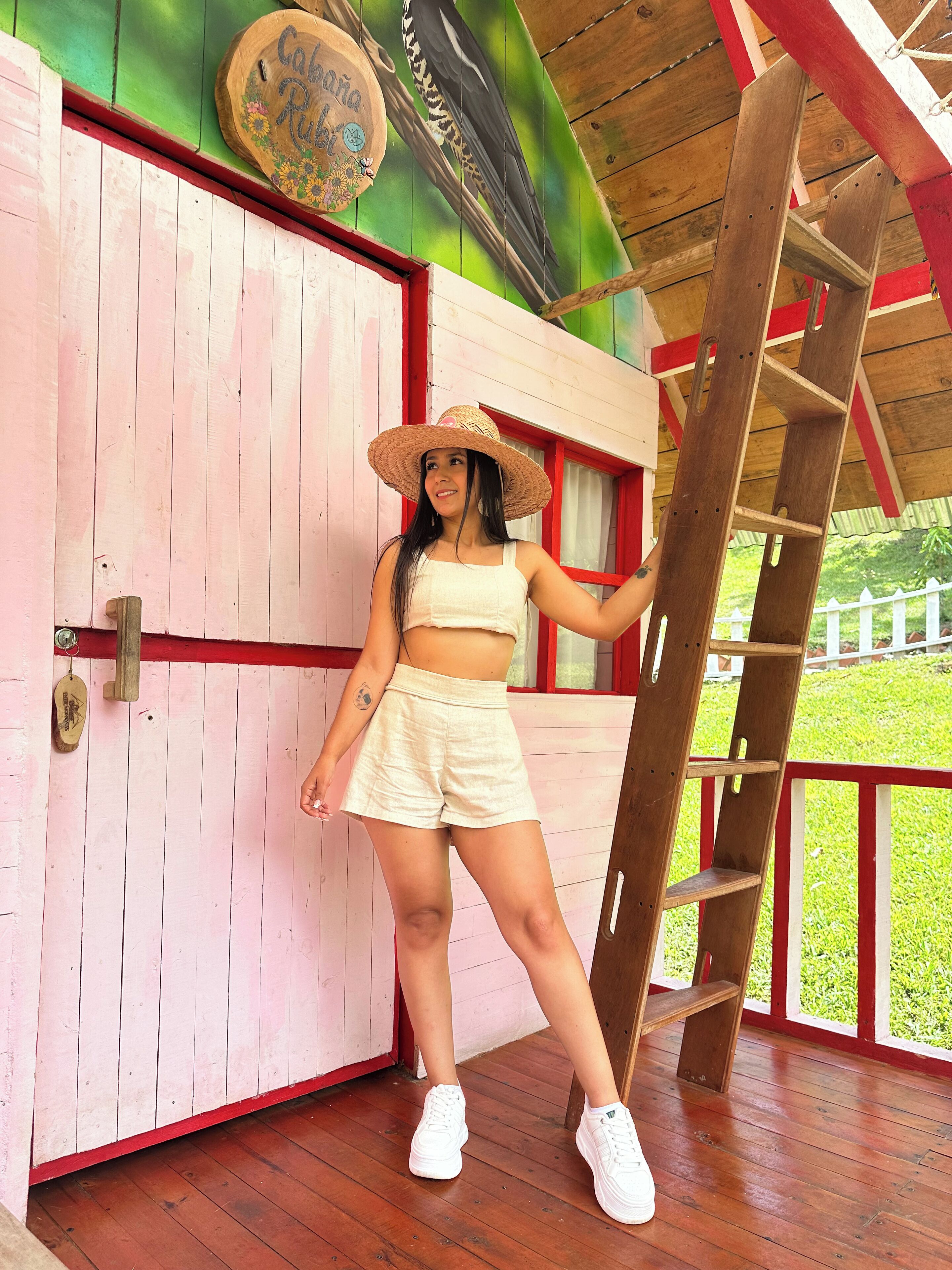 Una persona sobre una cubierta de madera, con una escalera, una puerta rosa y un mural de un ave.
