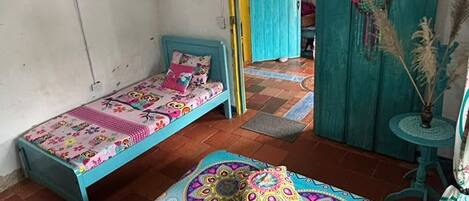 A room with two beds, a chandelier, a dreamcatcher, and a small table with a plant.