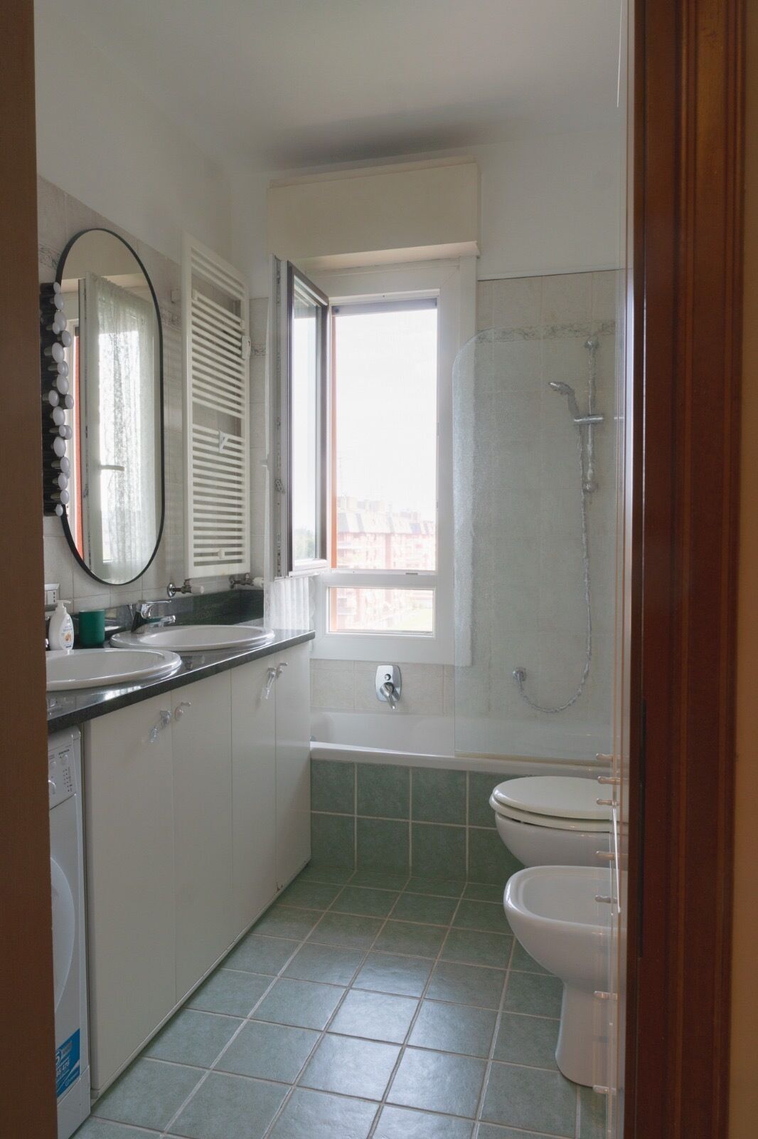 A bathroom with a window, a bathtub, and a toilet.
