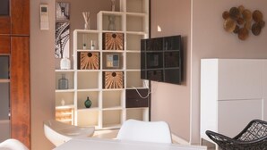 A modern living room with a white dining table, white chairs, a wooden cabinet, a white shelving unit with decorative items, and a black chair. - FORUM-Matteotti 12  (Assago)