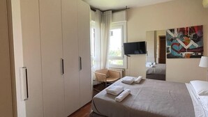 A hotel room with a bed, a chair, a TV, and a painting on the wall. - FORUM-Matteotti 12  (Assago)