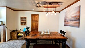 A dining area with a wooden table, chairs, a chandelier, and a painting on the wall. - Snowed Inn Brian Head Condo Sleeps 6 (Brian Head)