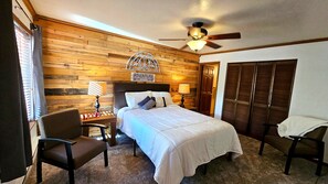 A hotel room with a wooden wall, a bed with white bedding, two bedside lamps, a ceiling fan, and a sign that reads 'ADVENTURE awaits'. - Snowed Inn Brian Head Condo Sleeps 6 (Brian Head)