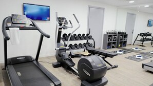 Un gimnasio con cintas de correr, elípticas y un soporte para pesas.