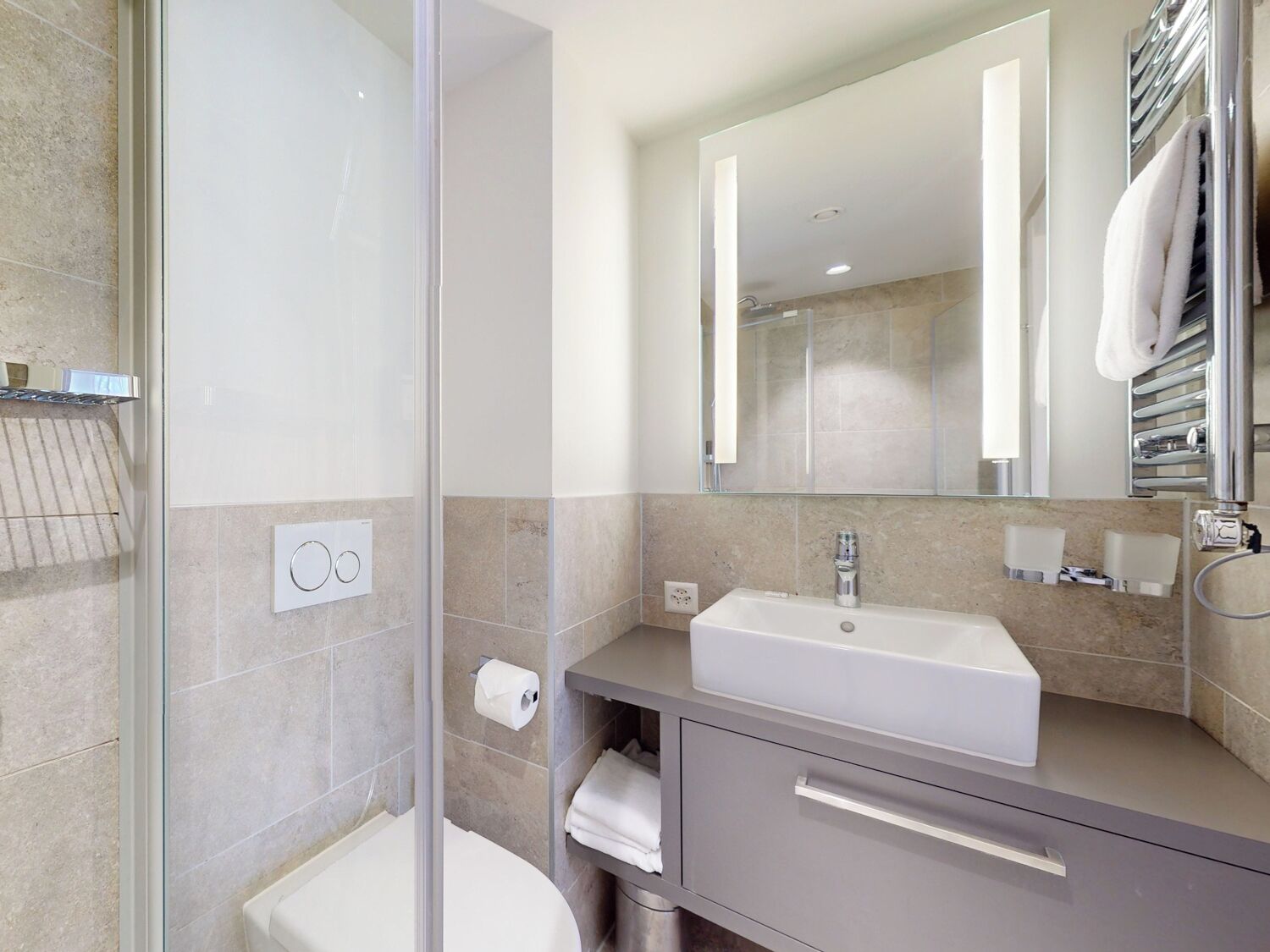 A modern bathroom with a glass shower enclosure, a white sink, and a large mirror.