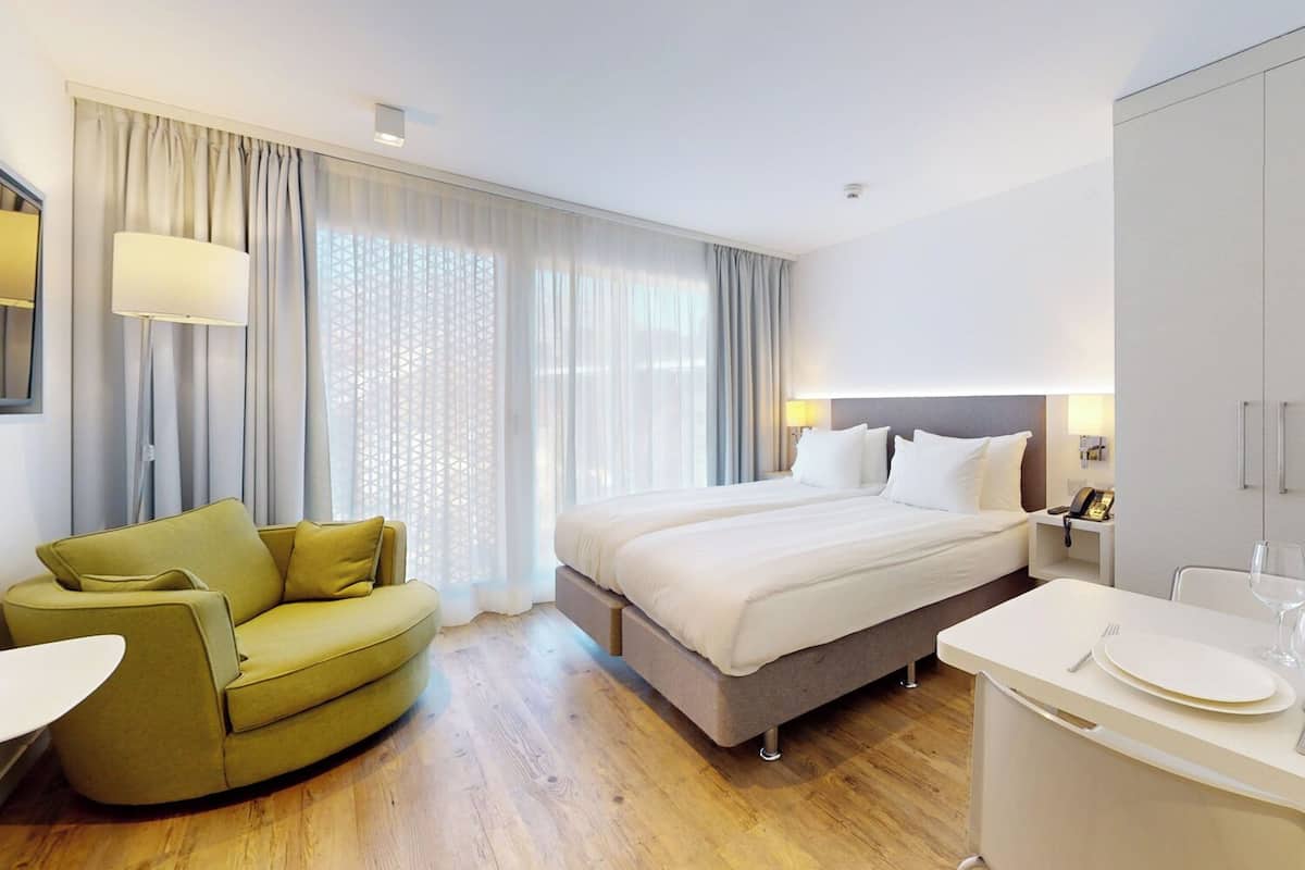 A hotel room with a bed, a sofa, a desk, and a minibar.