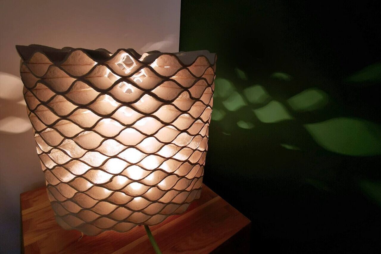 Una lámpara decorativa con un motivo de escamas de pez sobre un atril de madera.