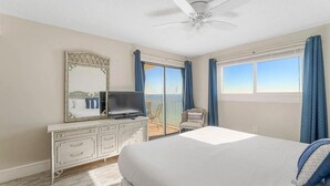 A bedroom with a bed, a dresser, a television, and a balcony with a view.