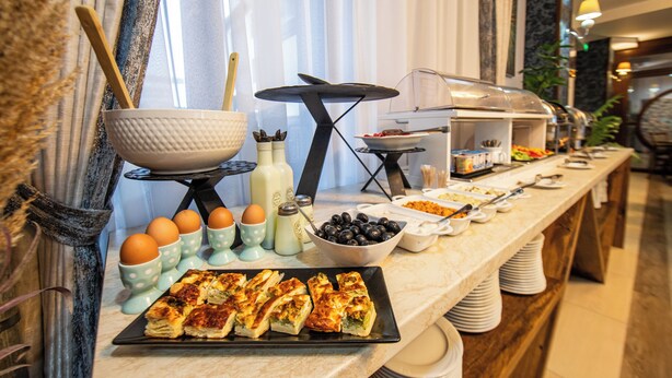 A buffet setup with various food items and utensils. - Hotel Stefani (Sibiu)