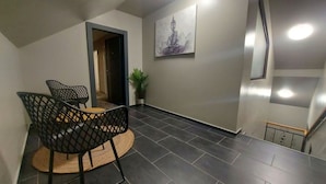 A modern interior with a dining area featuring black chairs and a small table, a potted plant, and a wall-mounted artwork. - Hotel Stefani (Sibiu)